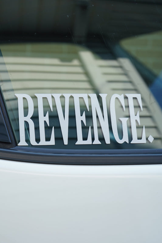Car window with 'REVENGE' decal on a blurred background