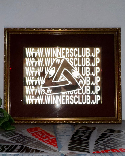 Framed artwork with 'WINNERSCLUB.JP' text on a table with branded paper.
